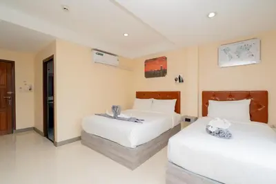 two beds in a room with white walls at Square One Hotel Patong in Patong Beach