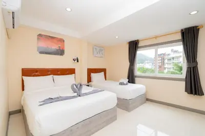 a bedroom with two beds and a window at Square One Hotel Patong in Patong Beach