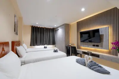 a hotel room with two beds and a flat screen tv at Square One Hotel Patong in Patong Beach