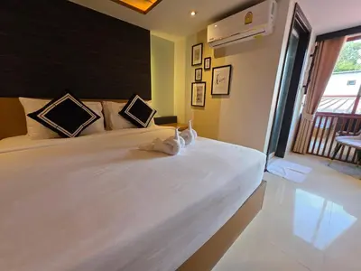 a large white bed in a room with a window at TT Naiyang Beach Phuket in Nai Yang Beach