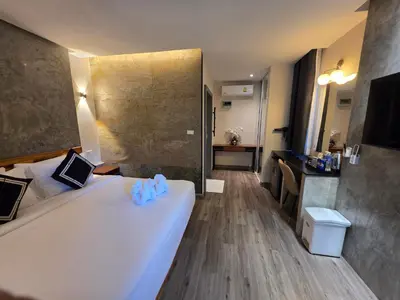 a hotel room with a large white bed and a bathroom at TT Naiyang Beach Phuket in Nai Yang Beach