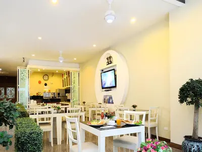 a dining room with white tables and white chairs at Pimrada Hotel in Patong Beach