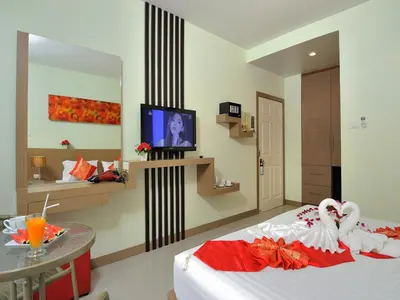 a room with a bed with a tv and a table at Pimrada Hotel in Patong Beach