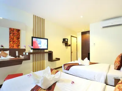 a hotel room with two beds and a flat screen tv at Pimrada Hotel in Patong Beach