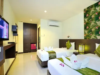a hotel room with two beds and a flat screen tv at Pimrada Hotel in Patong Beach