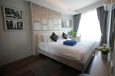a bedroom with a large bed with a large window at 6-Ave Surin Apartment in Surin Beach