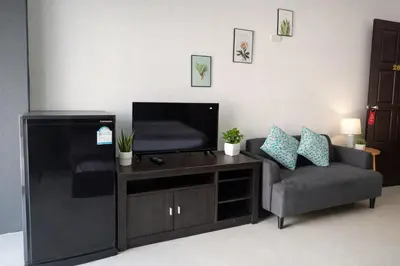 a living room with a chair and a flat screen tv at Happy Fish Guesthouse in Patong Beach