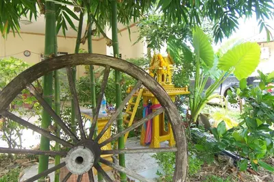 an old wooden wagon in a garden with trees at Phuket Airport Overnight Hotel in Nai Yang Beach