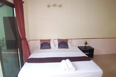 a bedroom with a large white bed with blue pillows at Phuket Airport Overnight Hotel in Nai Yang Beach
