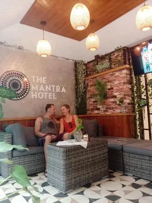 a man and woman sitting on a couch in a restaurant at The Mantra Hotel Kata Noi in Kata Beach