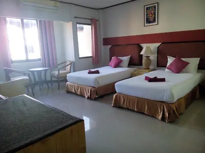 a hotel room with two beds and a table at Pro Andaman Place in Karon Beach