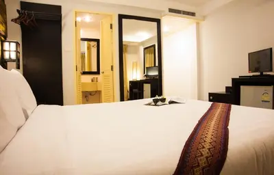 a bedroom with a white bed and a television at Crystal Inn in Phuket Town