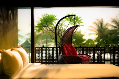 a chair sitting next to a bed on a balcony at Villa Saanti in Natai Beach