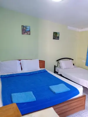 a bedroom with two beds with blue sheets at Nit Guest House in Kata Beach