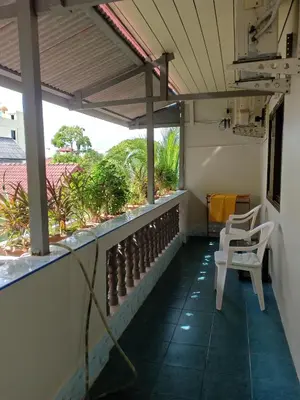 a balcony with two white chairs and a view at Nit Guest House in Kata Beach