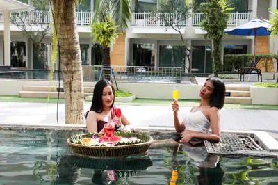 two women sitting in a swimming pool with glasses of wine at A2 Pool Resort - SHA Plus in Phuket Town
