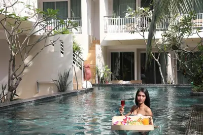 a woman in a pool with a cake and a drink at A2 Pool Resort - SHA Plus in Phuket Town