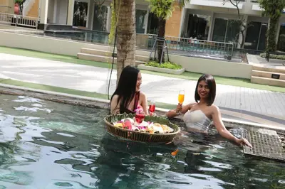 two women sitting in the water with a basket of food at A2 Pool Resort - SHA Plus in Phuket Town