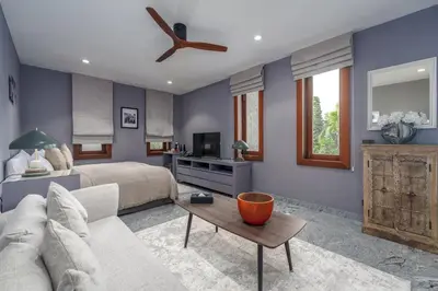 a bedroom with a bed and a ceiling fan at Baan Phu Prana Boutique Villa in Surin Beach