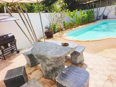 a stone table and chairs next to a pool at Thai family rawai Swimming pool villa Hotel in Rawai Beach