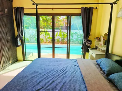 a bedroom with a bed and a view of a pool at Thai family rawai Swimming pool villa Hotel in Rawai Beach