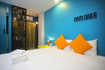 a bedroom with a large white bed with orange pillows at Nam Naka Boutique Hotel - SHA Plus in Phuket Town