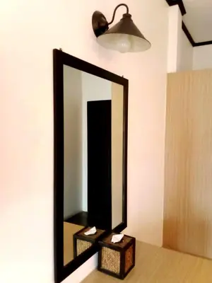 a mirror on a wall with a table and a light at SB Living Place Hotel Phuket Town in Phuket Town