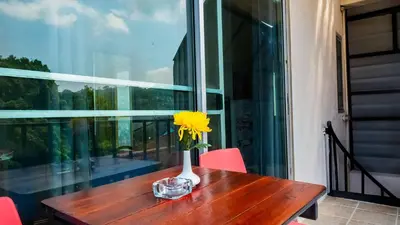 a vase with a yellow flower on a wooden table at Sabina Guesthouse Kamala in Kamala Beach