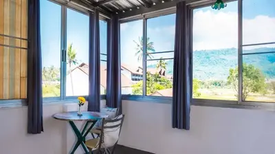 a table and chairs in a room with windows at Sabina Guesthouse Kamala in Kamala Beach