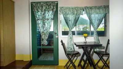a green door with a table and a window at Sabina Guesthouse Kamala in Kamala Beach