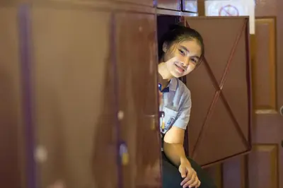a young girl is peeking out of a door at Baan Kamala Backpacker in Kamala Beach