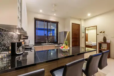 a kitchen with a counter top with chairs in it at Perfect 3br Pool Villa by Intira Villas in Rawai Beach