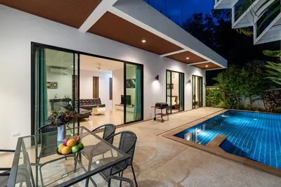 an indoor pool with a table and chairs next to a house at Modern 3br Boutique Pool Villa by Intira Villas in Rawai Beach
