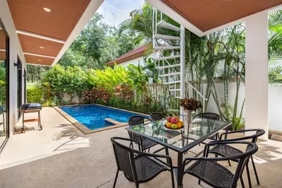 a patio with a table and chairs and a swimming pool at Modern 3br Boutique Pool Villa by Intira Villas in Rawai Beach