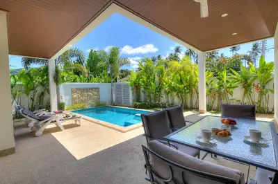 a patio with a table and chairs and a swimming pool at West facing 3br Boutique Pool Villa by Intira Villas in Rawai Beach