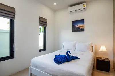 a bedroom with a white bed with a blue ribbon on it at Big Buddha View 3br Pool Villa by Intira Villas in Rawai Beach