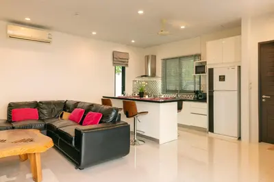 a living room with a leather couch and a kitchen at Thai-Themed 3br Boutique Villa by Intira Villas in Rawai Beach
