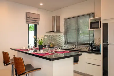 a kitchen with a counter with chairs and a refrigerator at Thai-Themed 3br Boutique Villa by Intira Villas in Rawai Beach