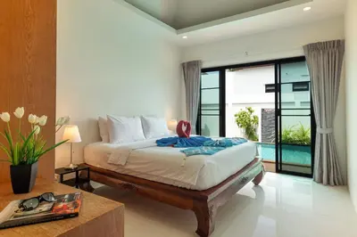 a bedroom with a bed with a table and a window at Thai-Themed 3br Boutique Villa by Intira Villas in Rawai Beach