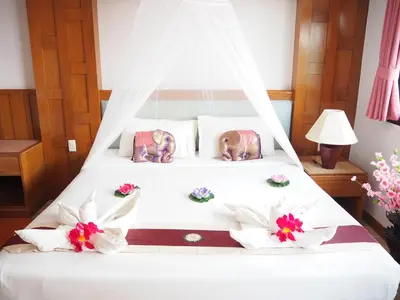 a bedroom with a white bed with flowers on it at Your Place Inn in Karon Beach