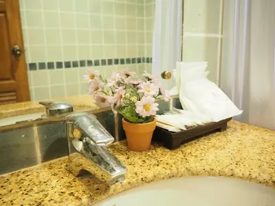 a bathroom counter with a sink with a vase of flowers at Your Place Inn in Karon Beach