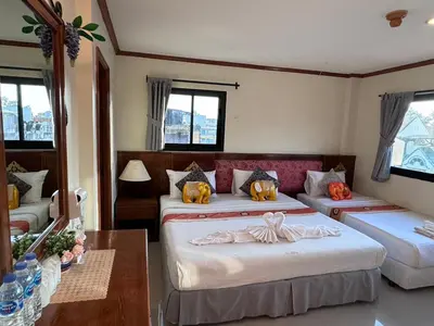 a bedroom with two beds and a table and windows at Your Place Inn in Karon Beach