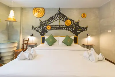 a bedroom with a large white bed with green pillows at Baan Kamala Fantasea Hotel in Kamala Beach