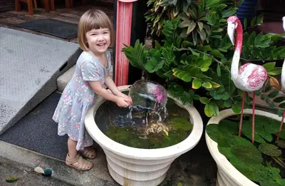 a little girl standing next to a bird bath at Baan Kamala Fantasea Hotel in Kamala Beach