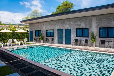 a swimming pool with chairs and umbrellas next to a building at Ongsa House in Bang Tao Beach