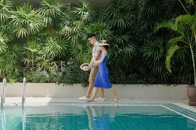 a man and a woman standing next to a swimming pool at Nonnee Hotel Kata Beach Phuket in Kata Beach