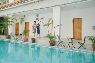 a man and a woman standing next to a swimming pool at Nonnee Hotel Kata Beach Phuket in Kata Beach