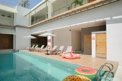 a swimming pool with chairs and a pink float next to a building at Nonnee Hotel Kata Beach Phuket in Kata Beach