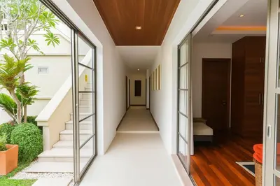 an internal corridor of a house with glass doors and stairs at The Residence Bantao Villa unit 121 in Bang Tao Beach