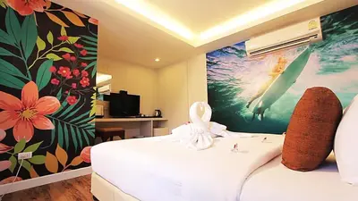 a bedroom with a white bed with a flower mural on the wall at Must Sea Hotel - SHA Hotel in Kata Beach